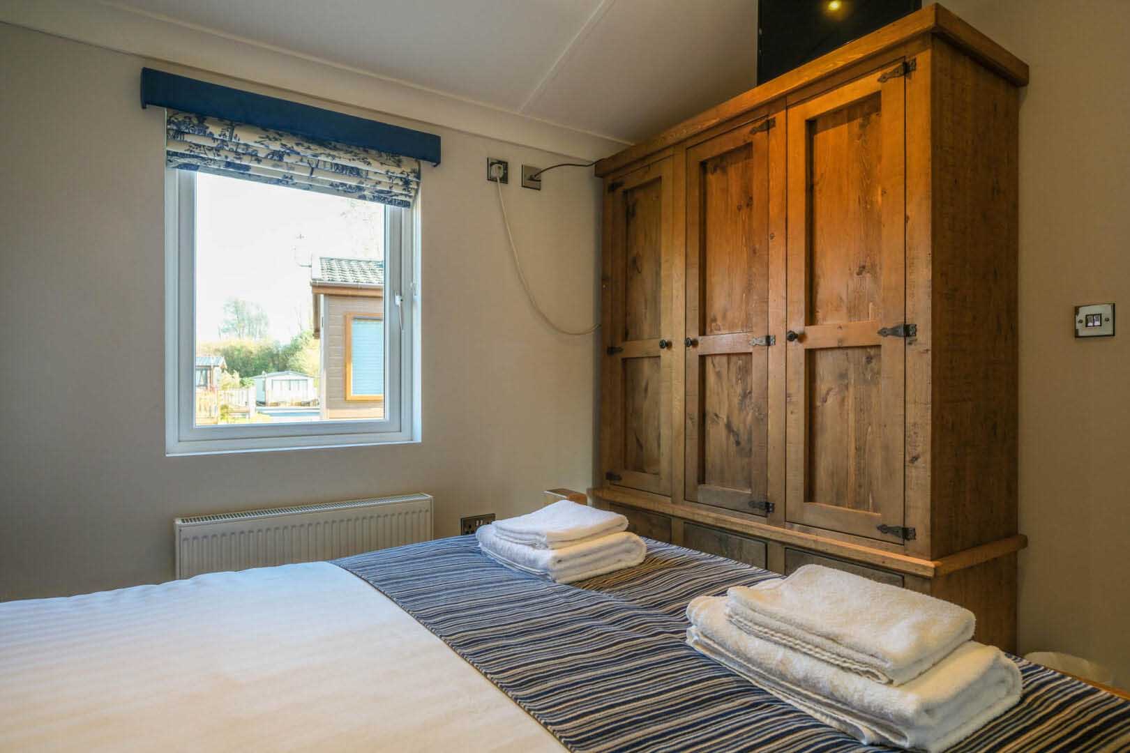 Bedroom double bed towel and dark wood wardrobe